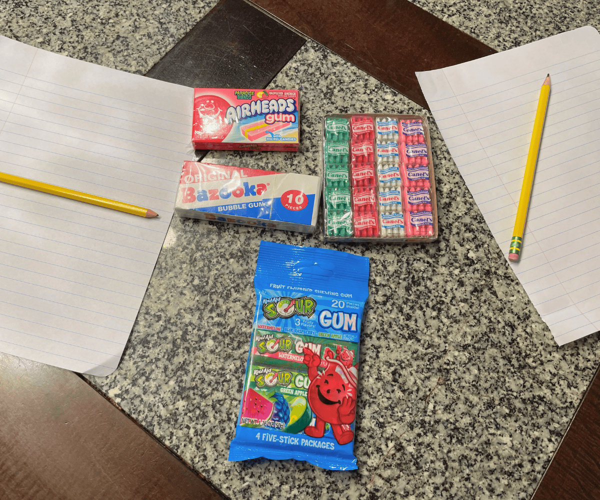 four different varieties of gums with two papers and pencils on a table