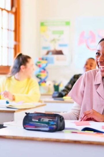 teen students in classroom smiling while working on financial literacy worksheets