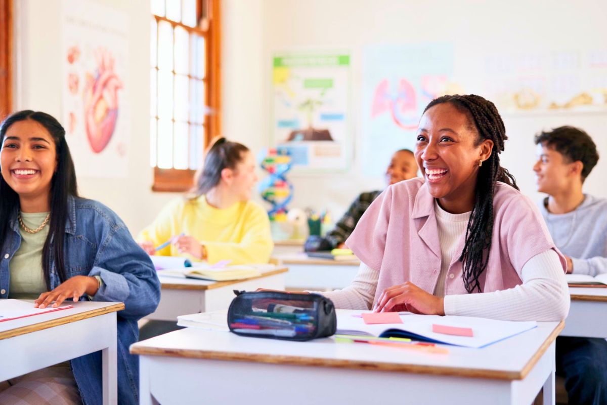 teen students in classroom smiling while working on financial literacy worksheets