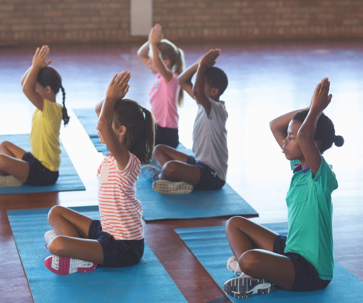 group of students in gymnasium on pads doing Yoga