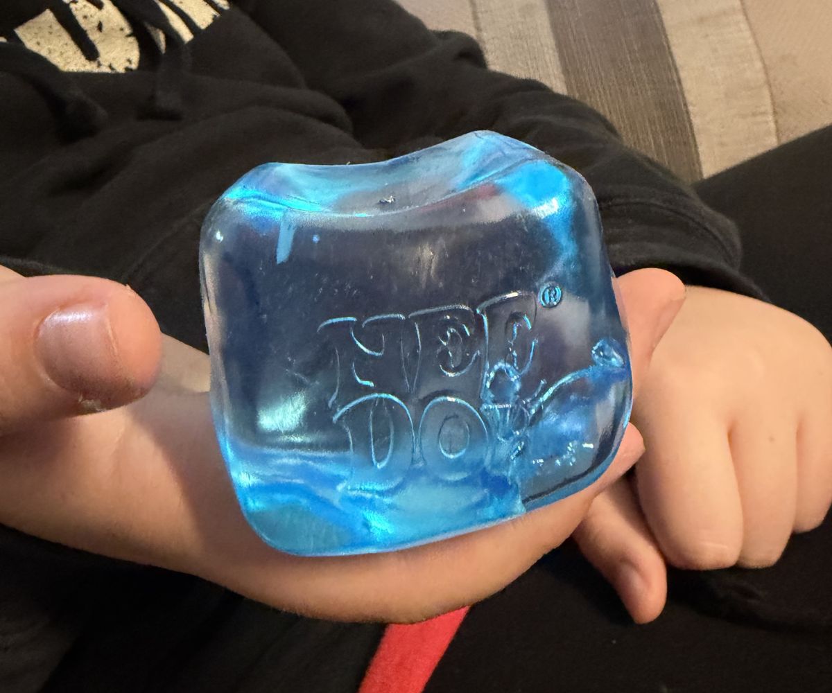 transparent blue NeeDoh cube in preteen boy's hand