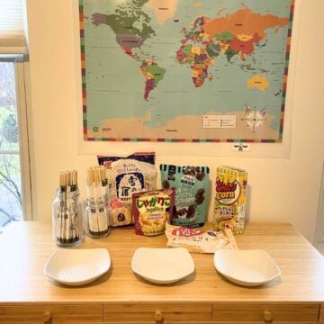 world map on wall, table filled with international snacks, chopsticks for everyone, and three bowls