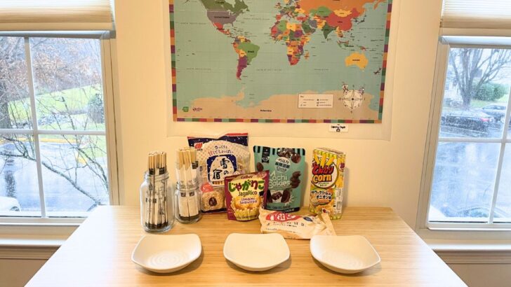 world map on wall, table filled with international snacks, chopsticks for everyone, and three bowls