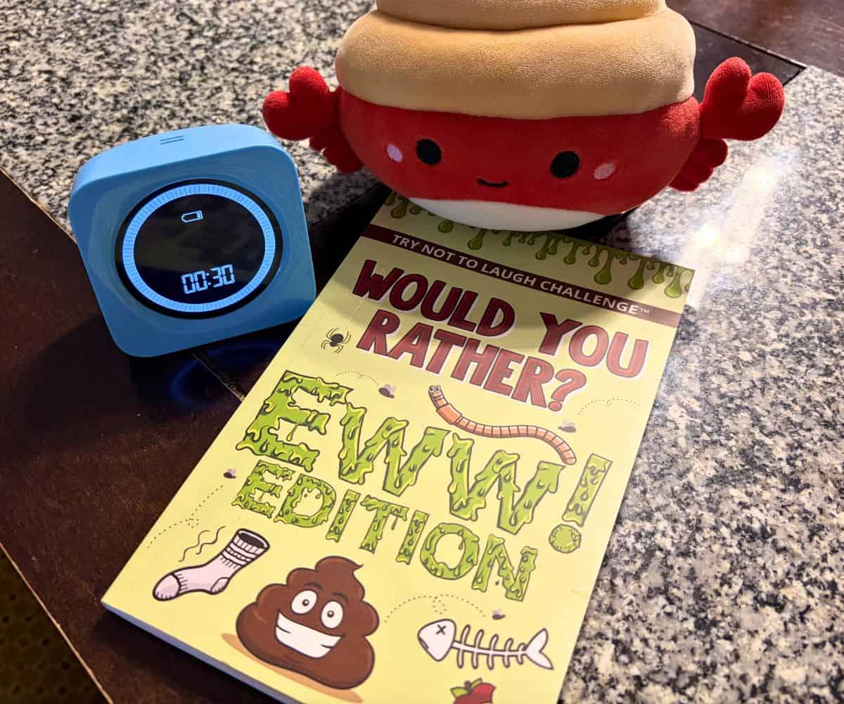 small plushie with Would You Rather Ewww Edition book and a timer set for 30 seconds on table