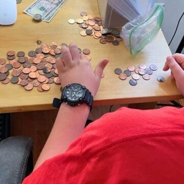 child counting coins and dollars on table to get ready for online shopping day spending