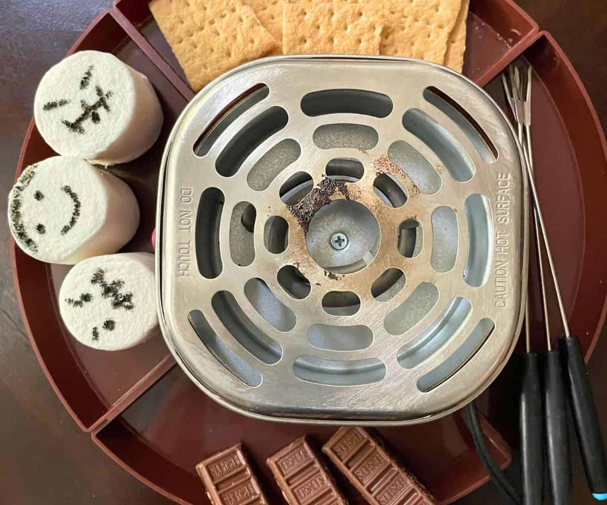 electric s'mores station with marshmallows that have edible faces drawn on them