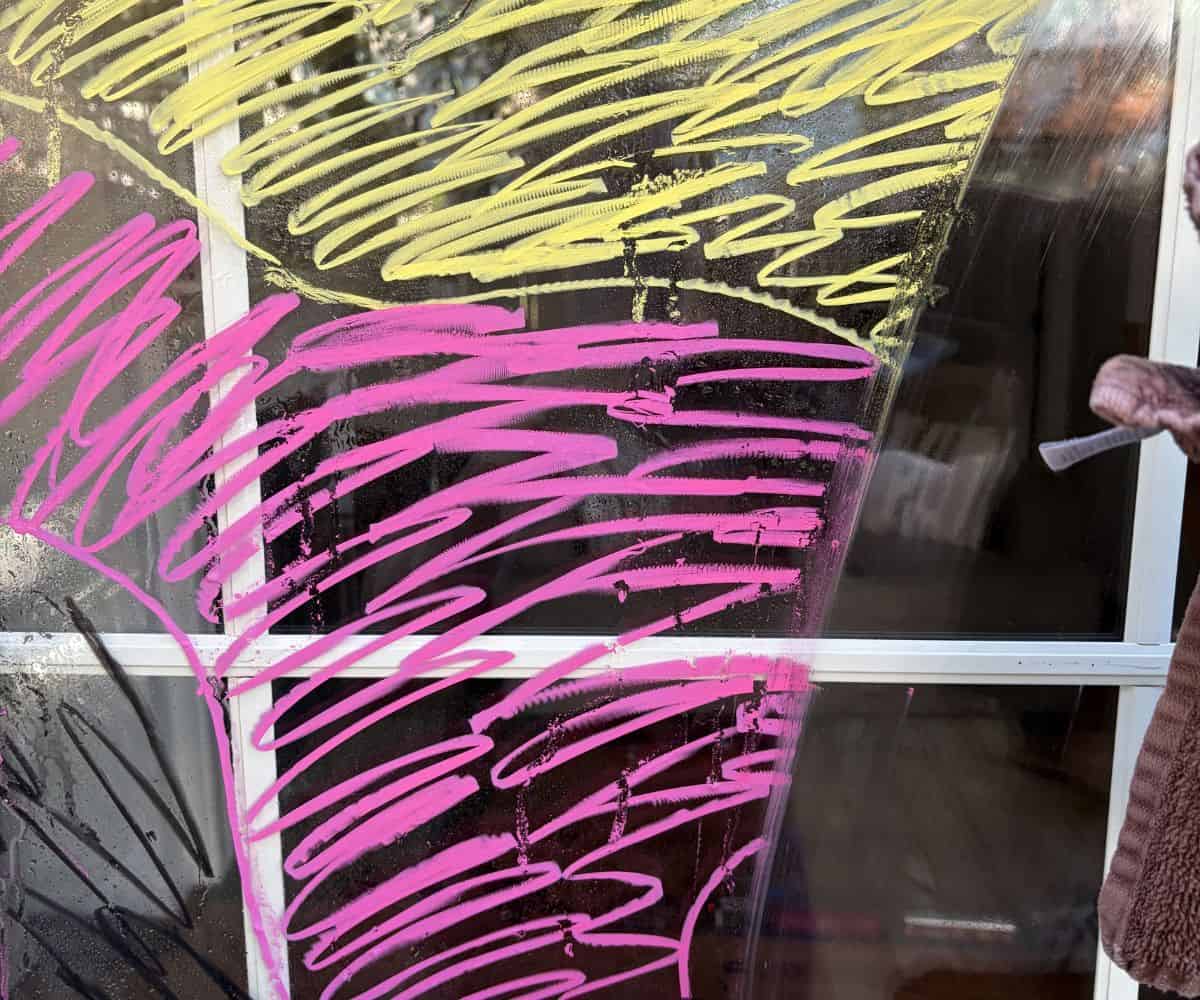 woman with damp washcloth, showing easy removal of the window mural