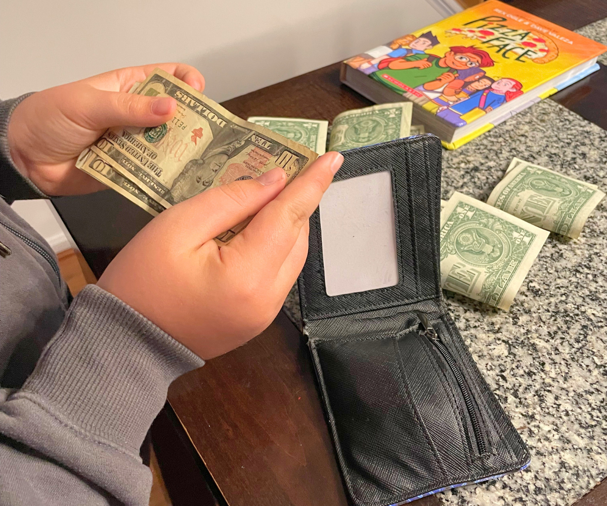 child counting money at a table with his wallet
