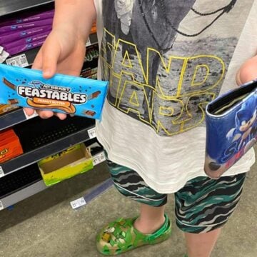 boy with wallet in one hand and Feastables in the other to buy