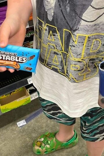 boy with wallet in one hand and Feastables in the other to buy