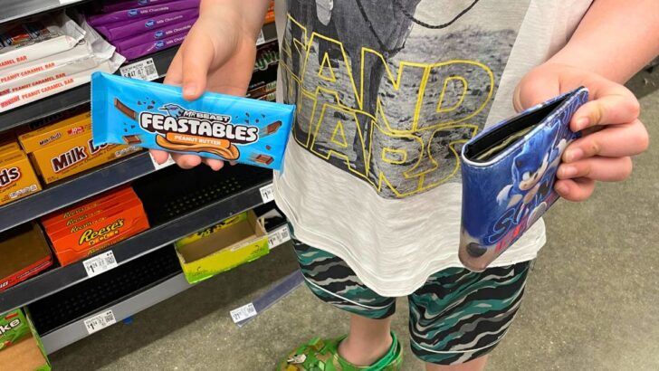 boy with wallet in one hand and Feastables in the other to buy
