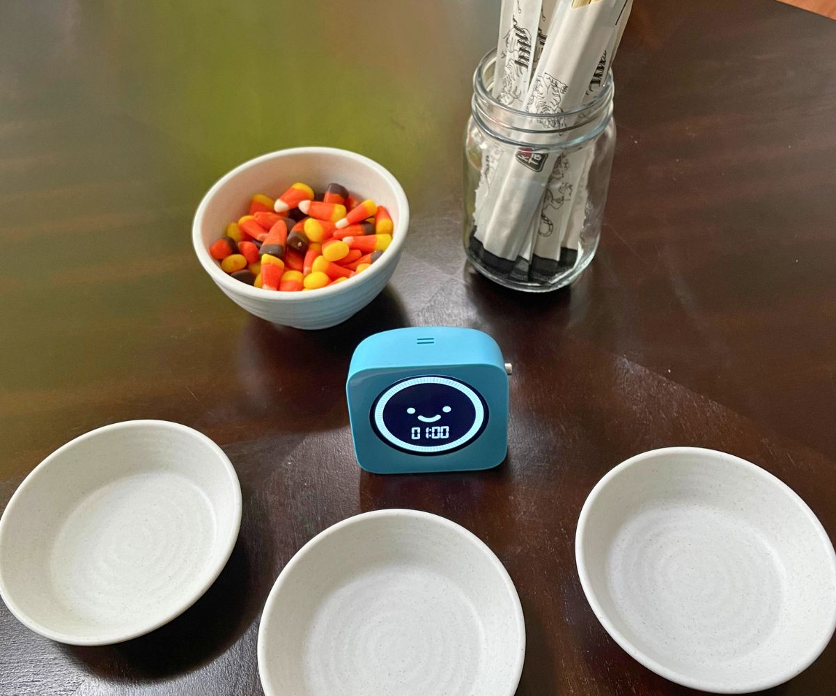 timer with a bowl of candy corn and a bunch of chopsticks