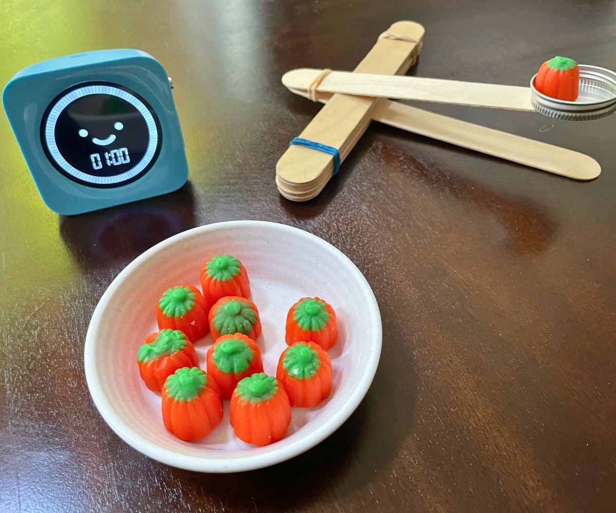 handmade catapult with mini pumpkin candy on it, and a timer