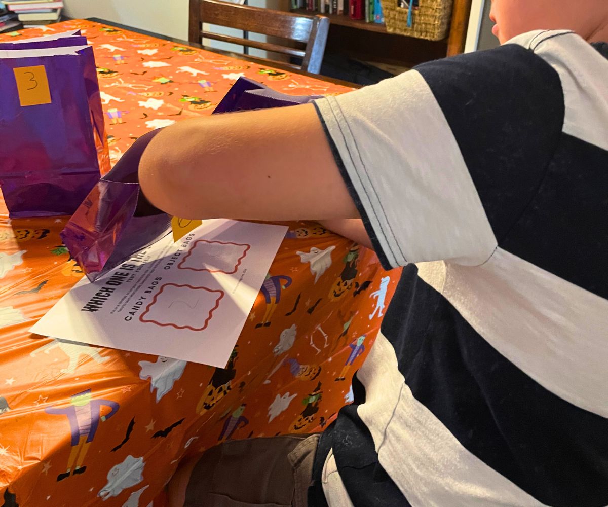 boy reaching into purple bag to feel and guess which bag has the candy
