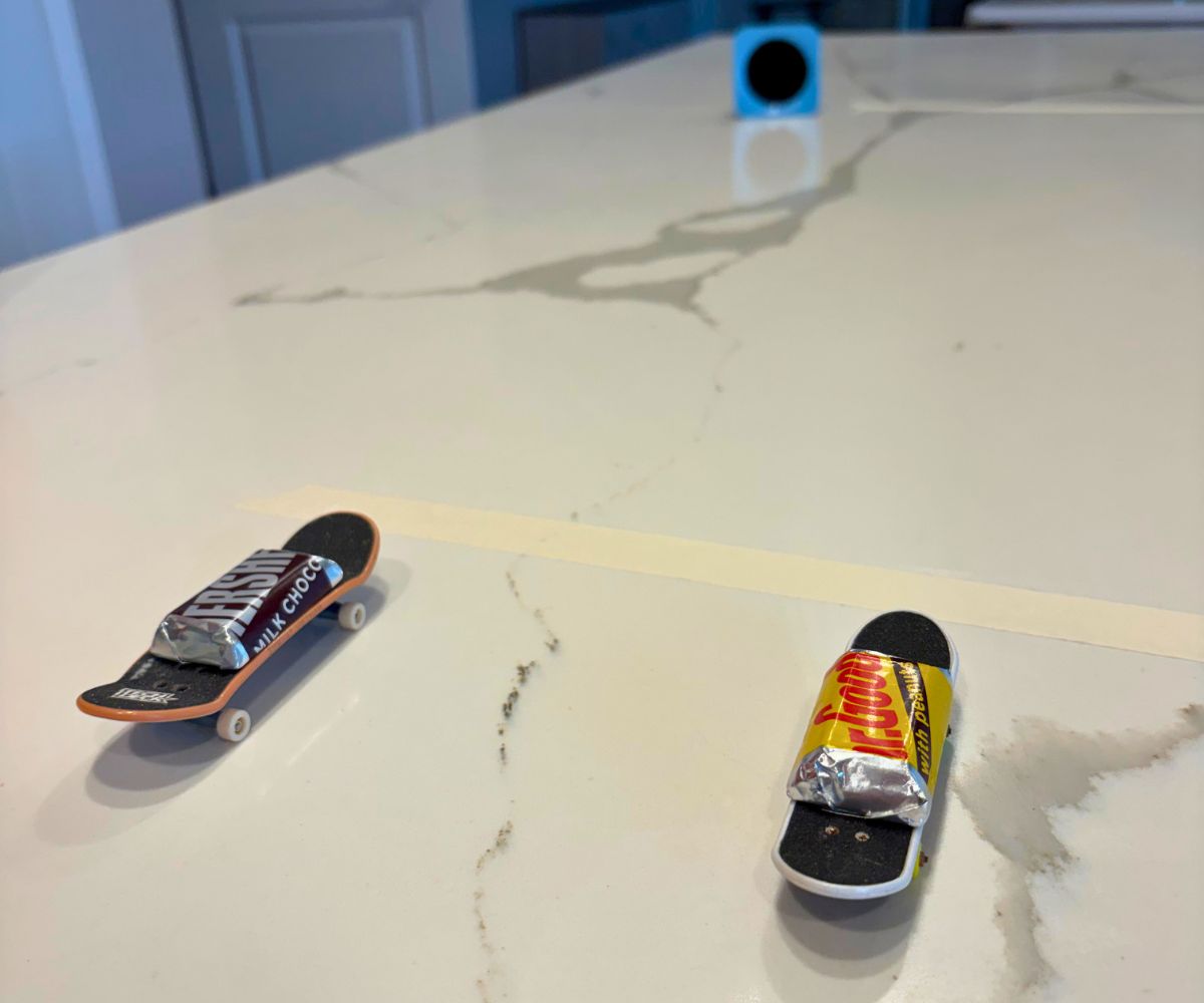 two tech decks on a smooth marble counter with a piece of candy, at the start line