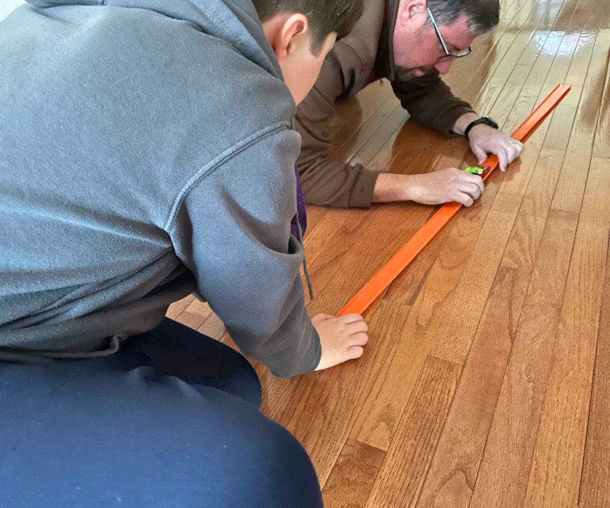 two guys working on connecting the car tracks and transporting a mini car with candy on it