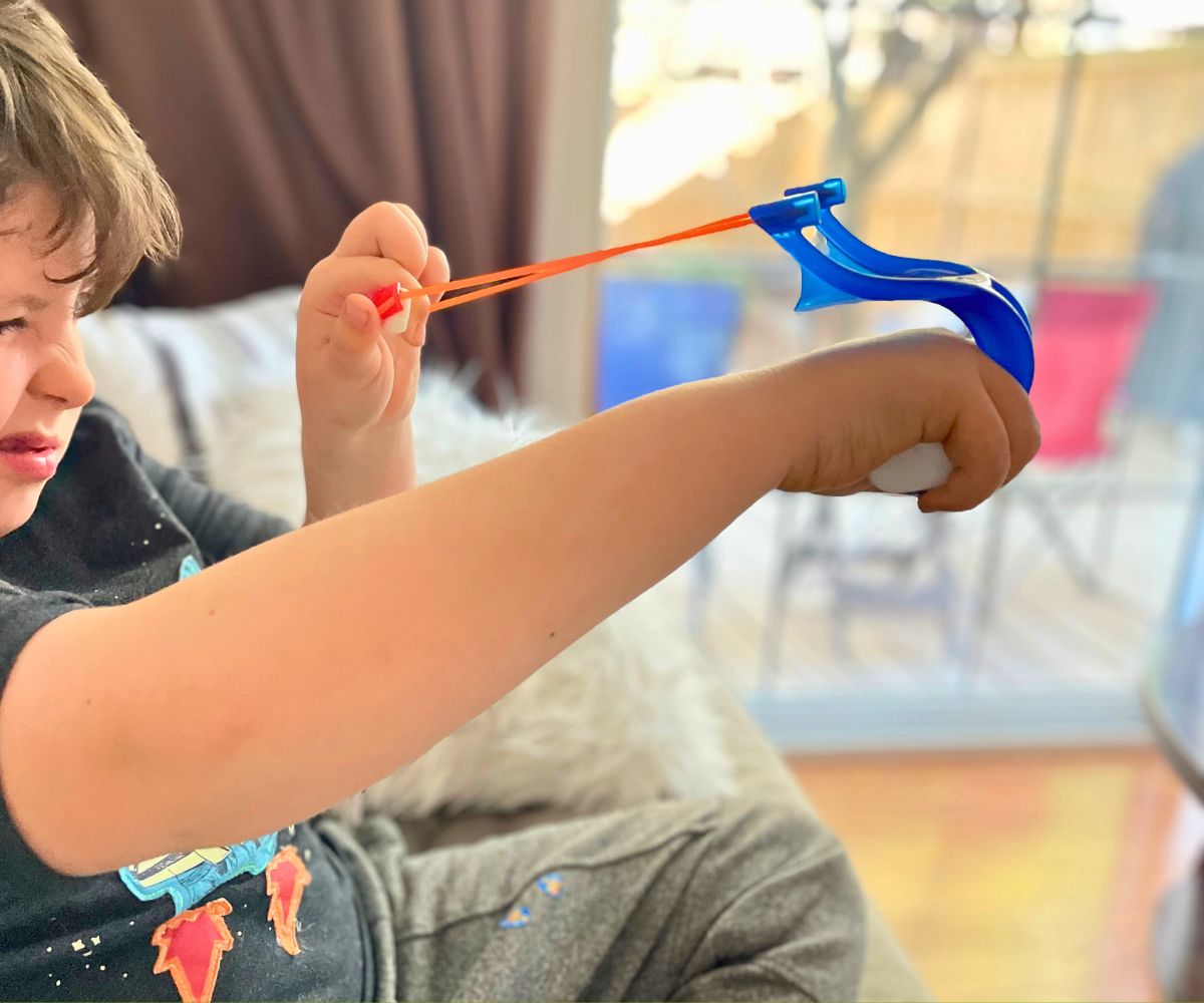 boy aiming marshmallow shooter with one eye closed
