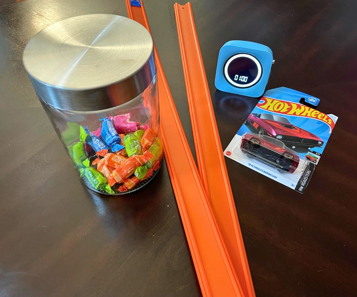 jar of wrapped candies, two car tracks, timer, and a hot wheels car